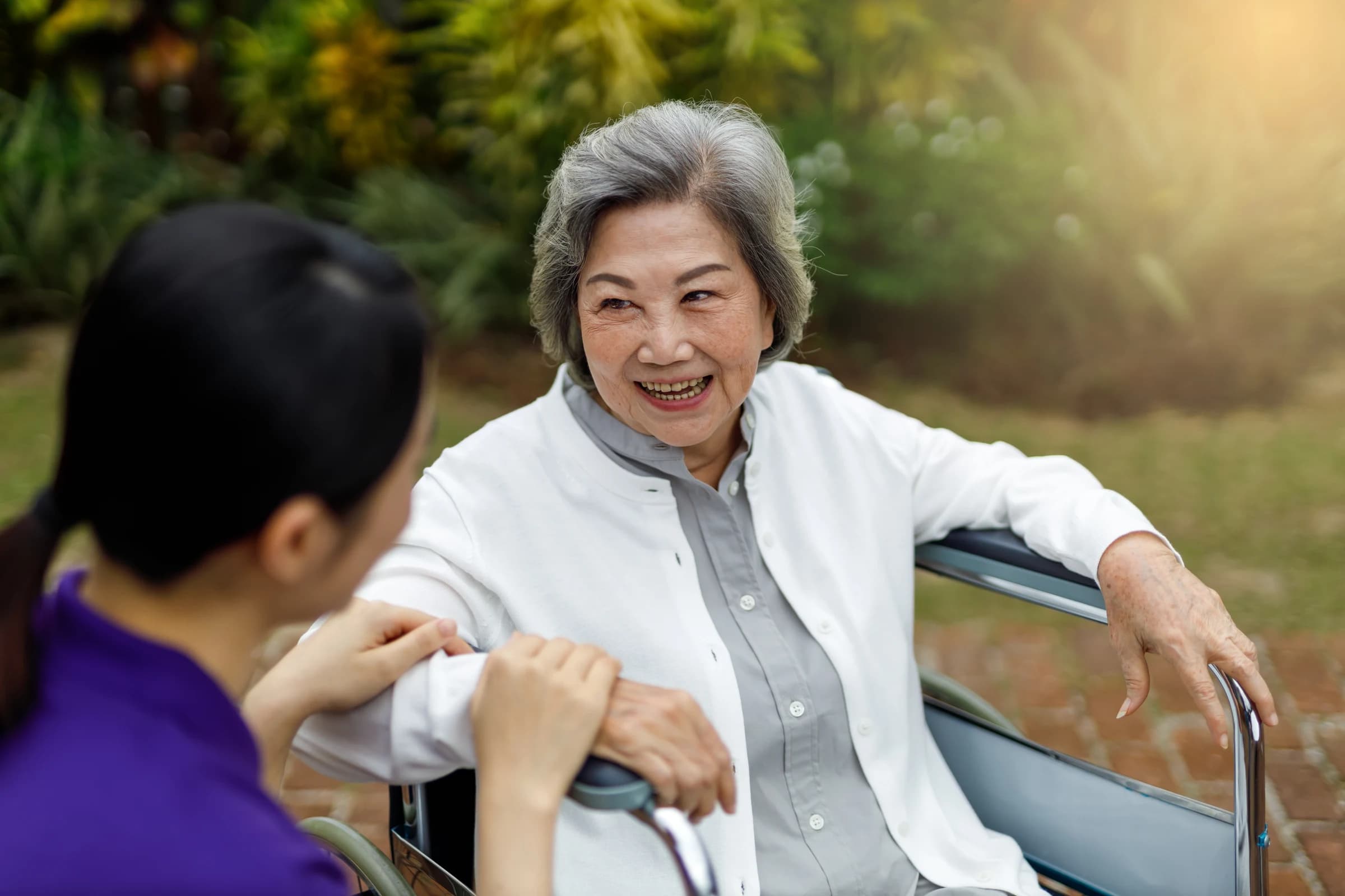A smiling senior spending time with a caregiver in a garden