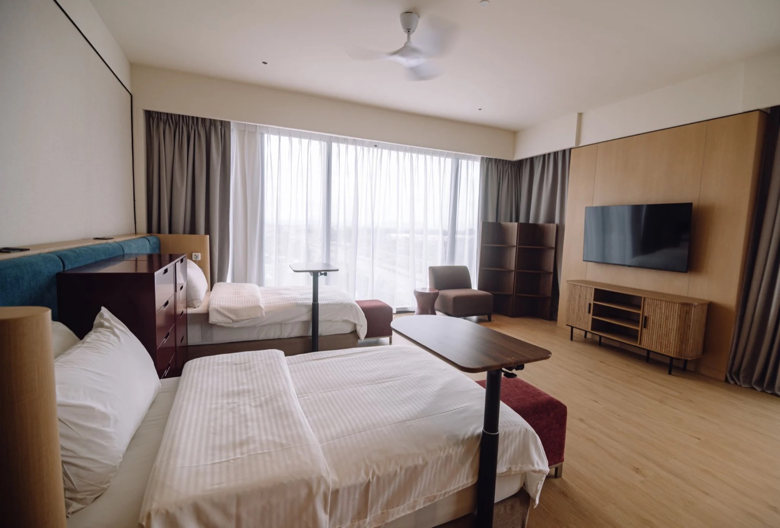 A twin room with two single beds and over-bed tables at Care Collective in Kuching
